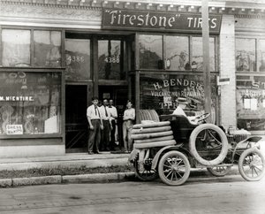 Hombres y camión de reparación de neumáticos reunidos fuera del concesionario de neumáticos H. Bender Firestone en 4388 Olive Street de Unknown